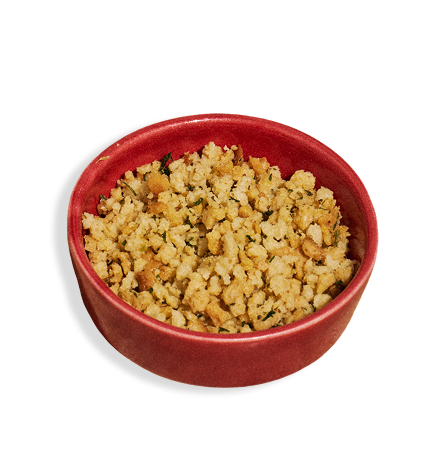 A small red bowl filled with a crumbled, golden-brown crunchy topping, photographed on a plain white background.