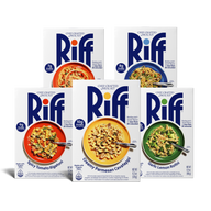 Five Riff chef-crafted meal kit boxes arranged in a studio setup, including Spicy Tomato Rigatoni, Sesame Ginger Noodles, Creamy Parmesan Cavatappi, and Garlic Lemon Rotini, plus a fifth box with a red plate of spaghetti in tomato sauce partially hidden behind the others.