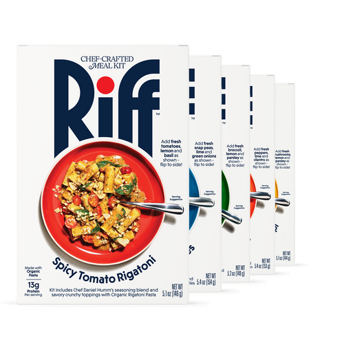 Five Riff chef-crafted meal kit boxes fanned out, led by Spicy Tomato Rigatoni in front with a red plate of pasta, followed by boxes for noodles, rotini, and cavatappi flavors in blue, green, orange, and yellow bowls, each box noting the fresh produce to add and stating the kit includes Chef Daniel Humm's seasoning blend.